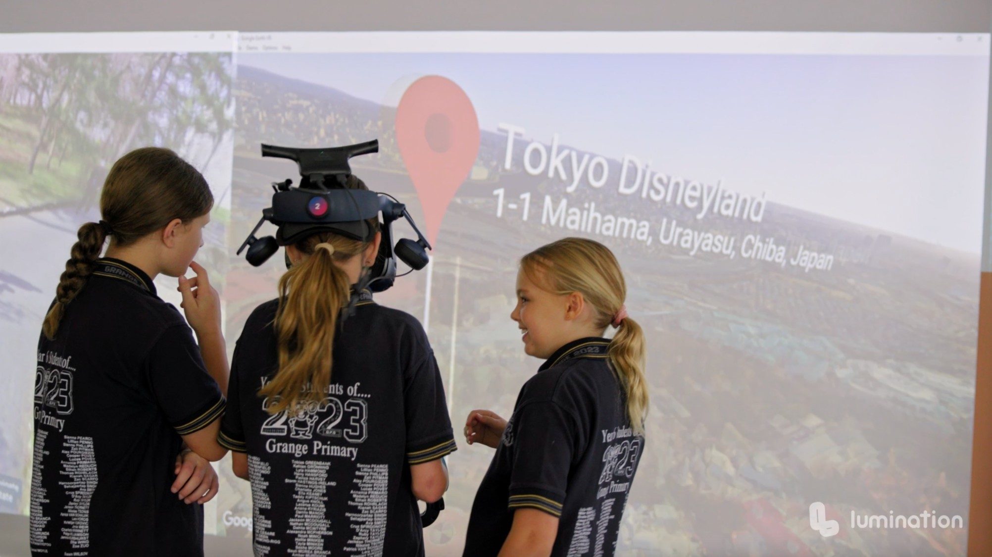 Student engagement using virtual reality at Grange with three students wearing virtual reality headsets and screen depicting where they are visiting in Google Earth: Tokyo Disneyland in Japan